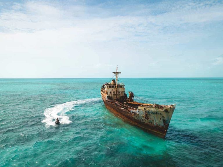 Person jet-skiing next to a shipwreck in the ocean
