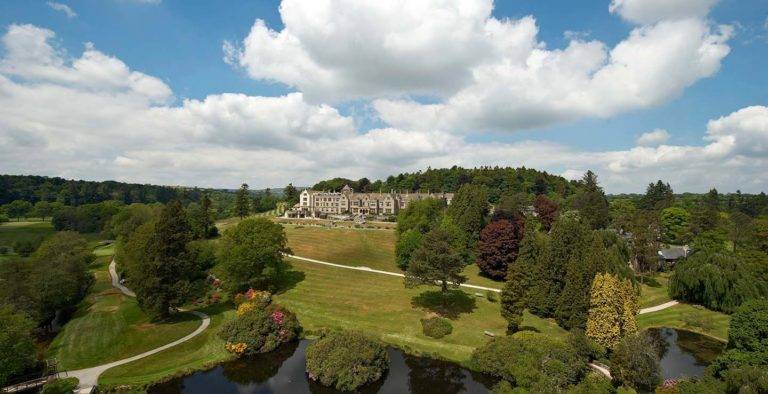 View of Bovey Castle surrounded by extensive lawn and various trees