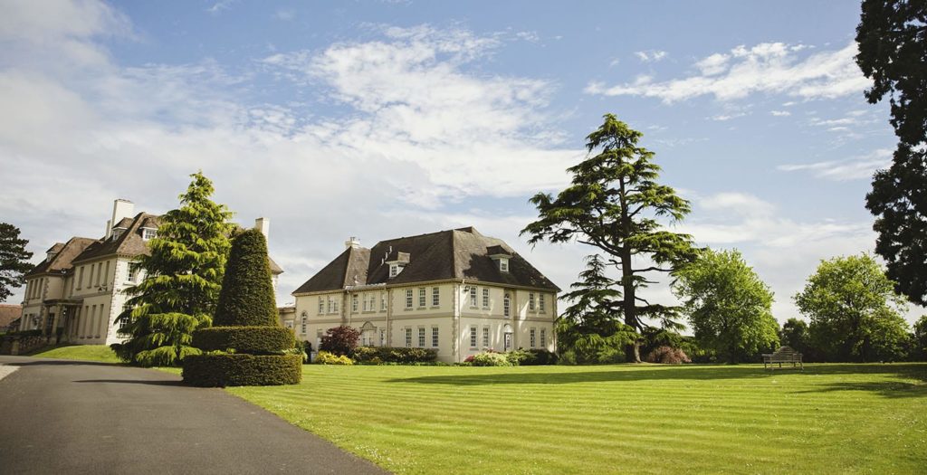 Brockencote hall building exterior on a sunny day with expansive, manicured lawn