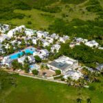 Aerial view of the Cap Cove Resort property, beach, villas, and pool