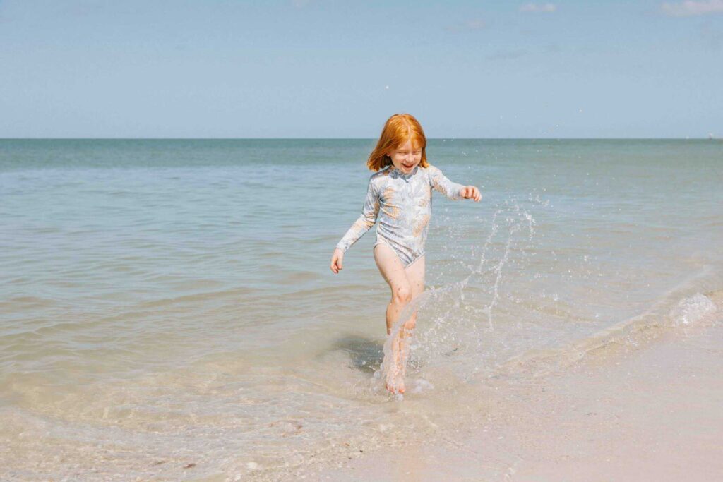 Young girl splashing in the water at Naples Beach