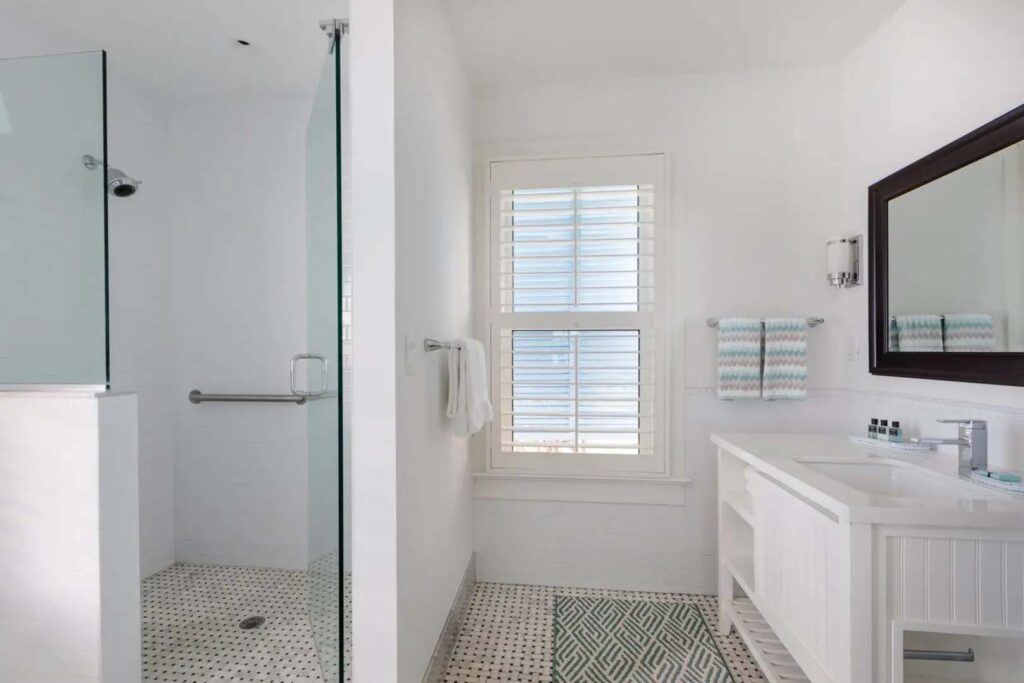 Coquina Cottage master bathroom with standalone shower, single vanity, and mirror at the Capri Inn