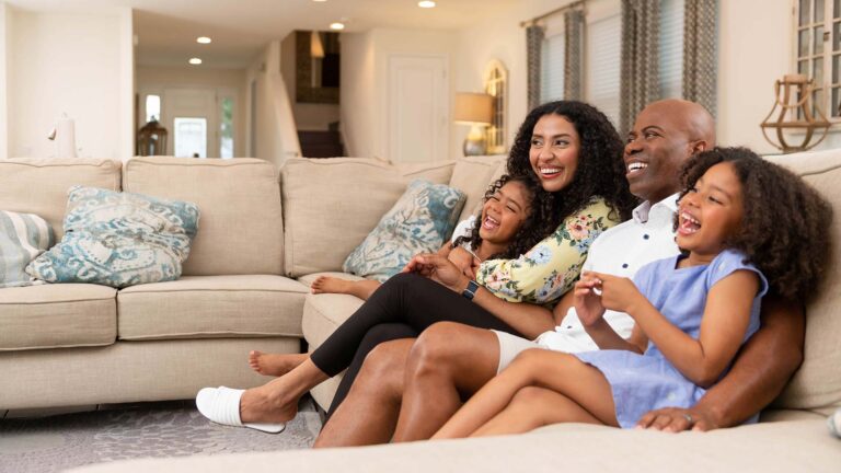 Family of four relaxing on a couch in their Encore Resort Residence